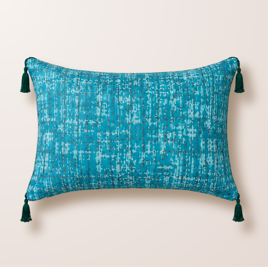 Coussin bleu turquoise/aqua, avec des froufrou bleu plus foncé aux quatre coins.