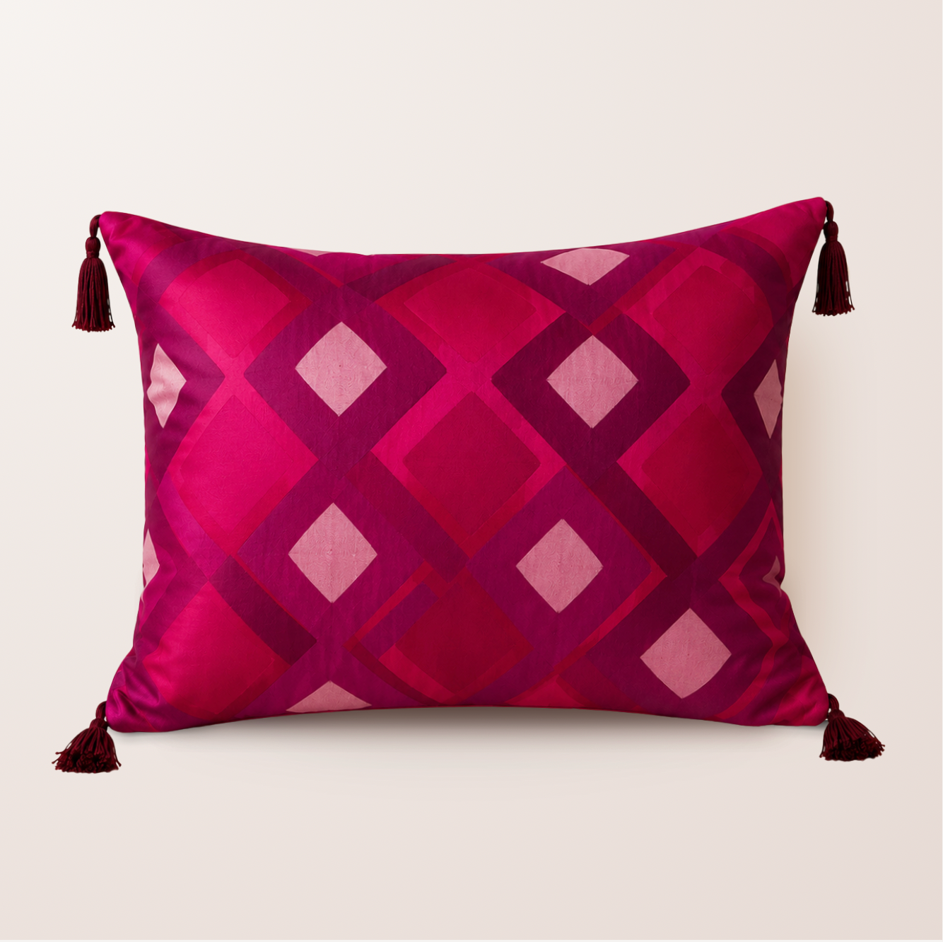 Coussin décoratif rose fushia avec des motifs géométriques violets et des pompons rose foncé à chaque extrémités. 