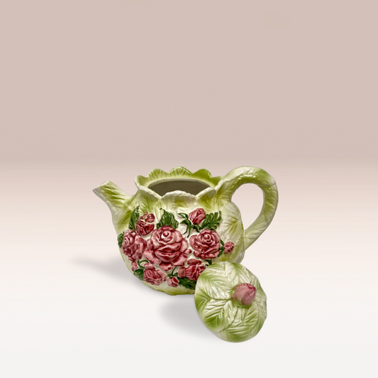 Théière en barbotine de couleur vert clair et texture feuille de chou. Des roses ornent les deux faces de la théière de forme ronde. Un poignet et un couvercle sont avec.