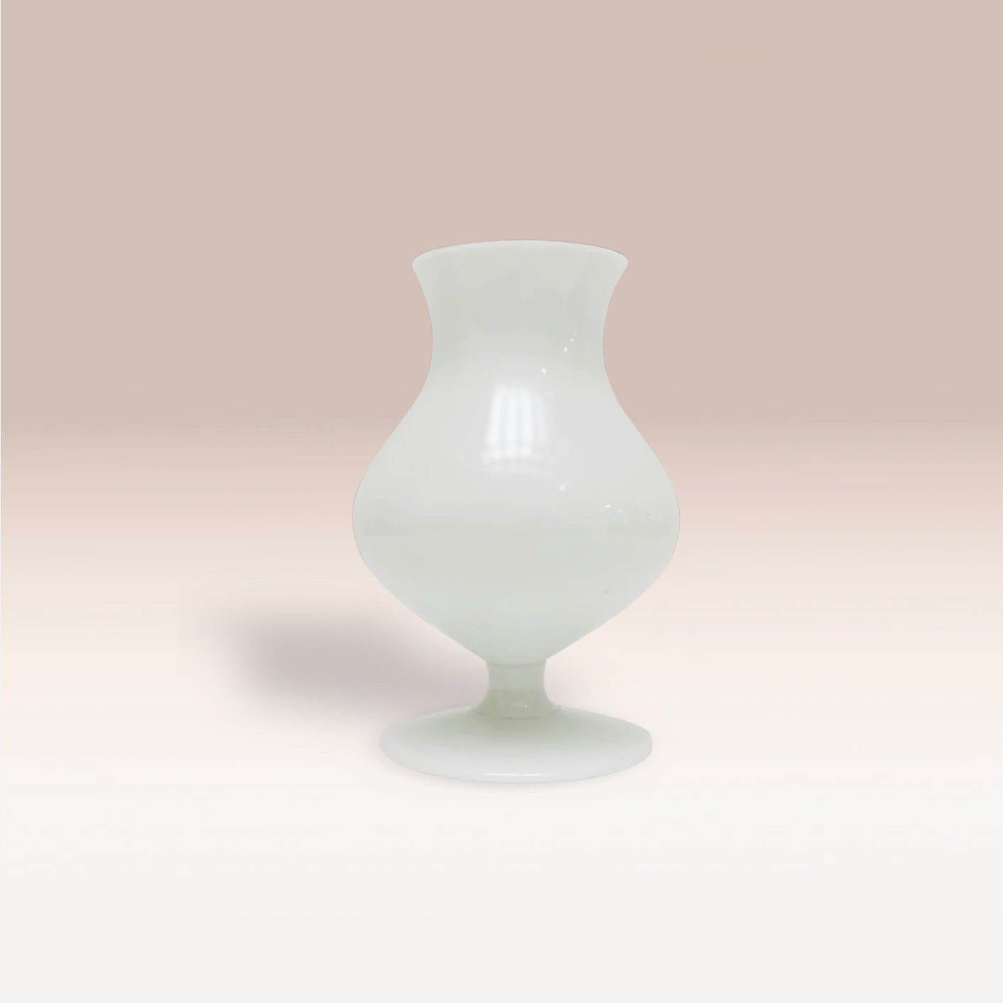 Petit vase en forme de goutte en opaline blanche. Texture lisse et polie qui réfléchit la lumière.