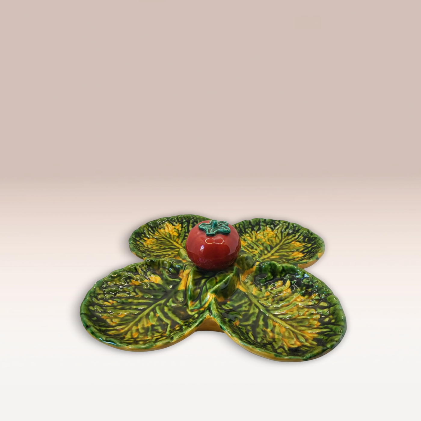 Plat en forme de feuille de chou de couleur vert avec des reflets jaunes avec quatre partie qui forme un trèfle. Une tomate se trouve au milieu du plat.